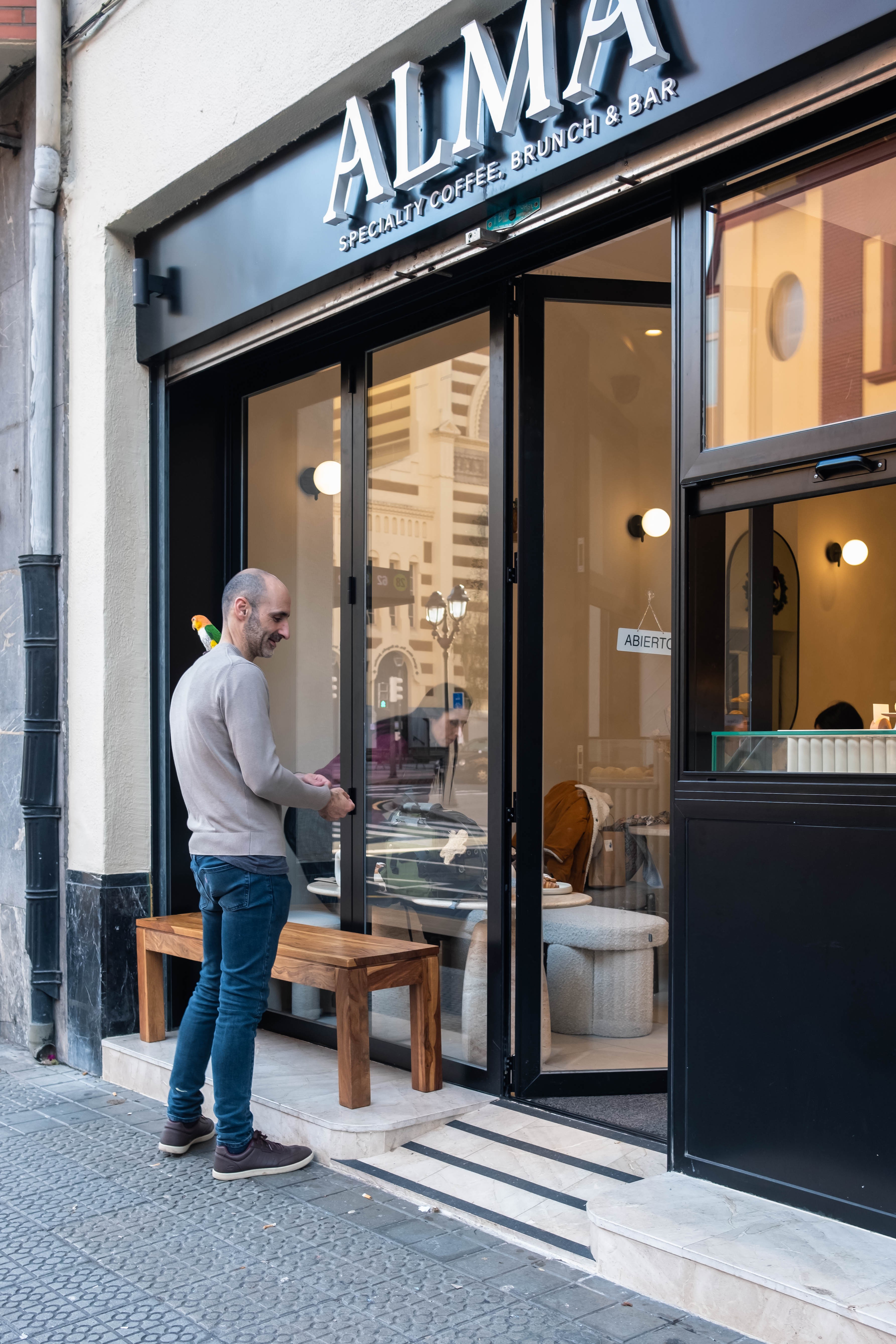Hombre con un loro en su hombro frente a un café en Indautxu. Bilbao, Bizkaia.