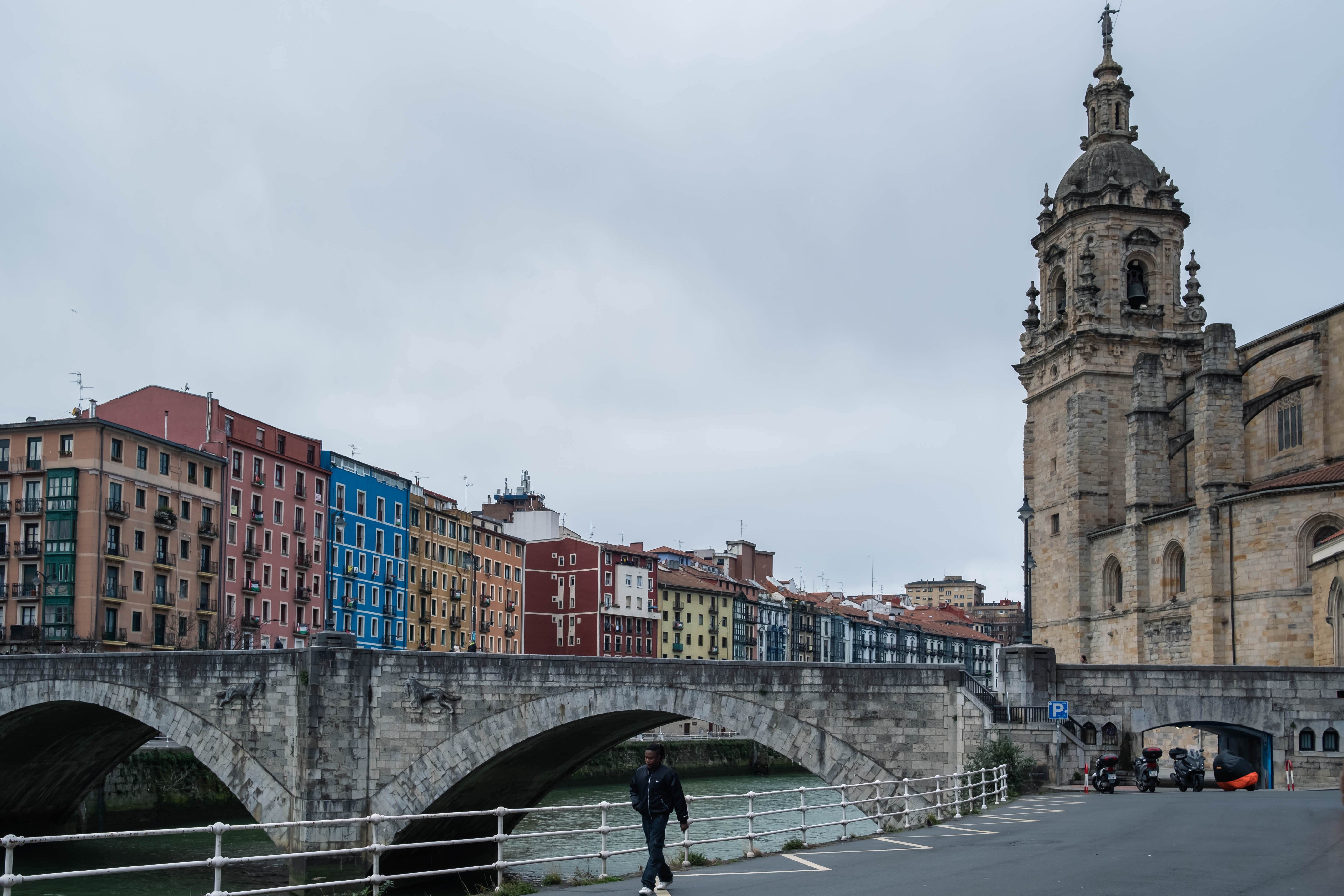 Hombre camina frente a la iglesia y el puente de San Antón. Bilbao, Bizkaia.