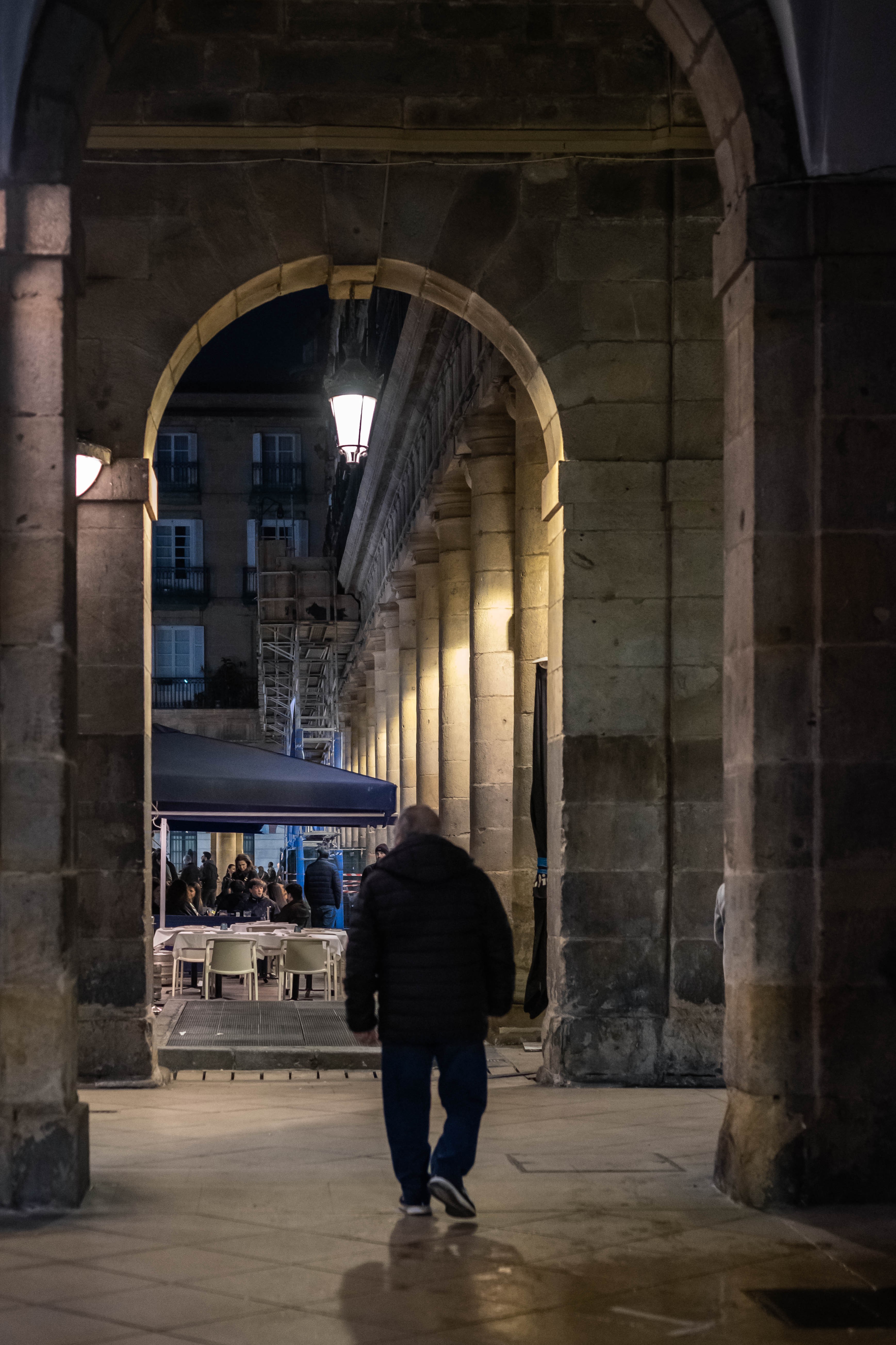 Un hombre camina bajo los arcos de la Plaza Nueva en el Casco Viejo. Bilbao, Bizkaia.