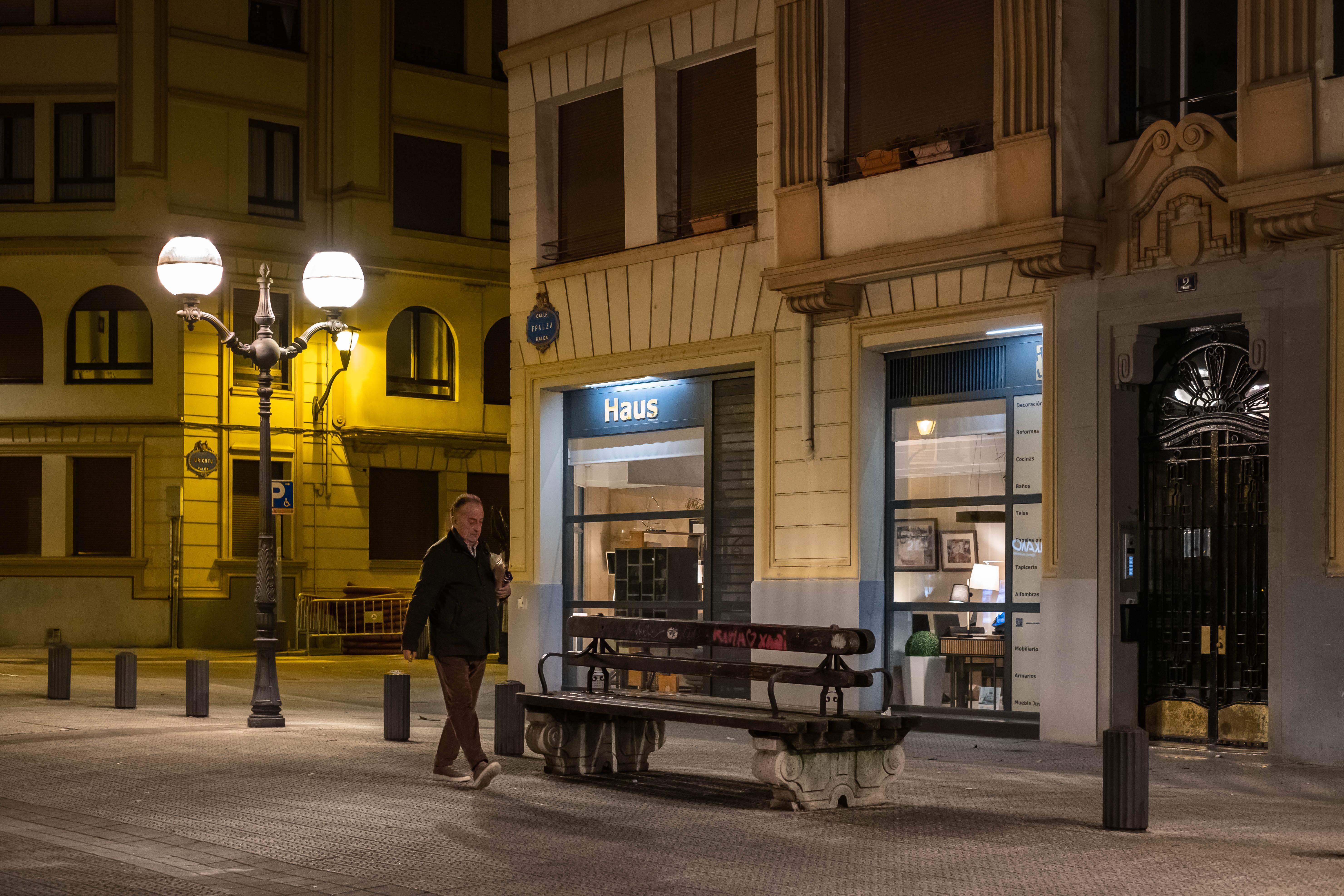 Un hombre camina iluminado por las farolas en una calle del barrio de Matiko. Bilbao, Bizkaia.