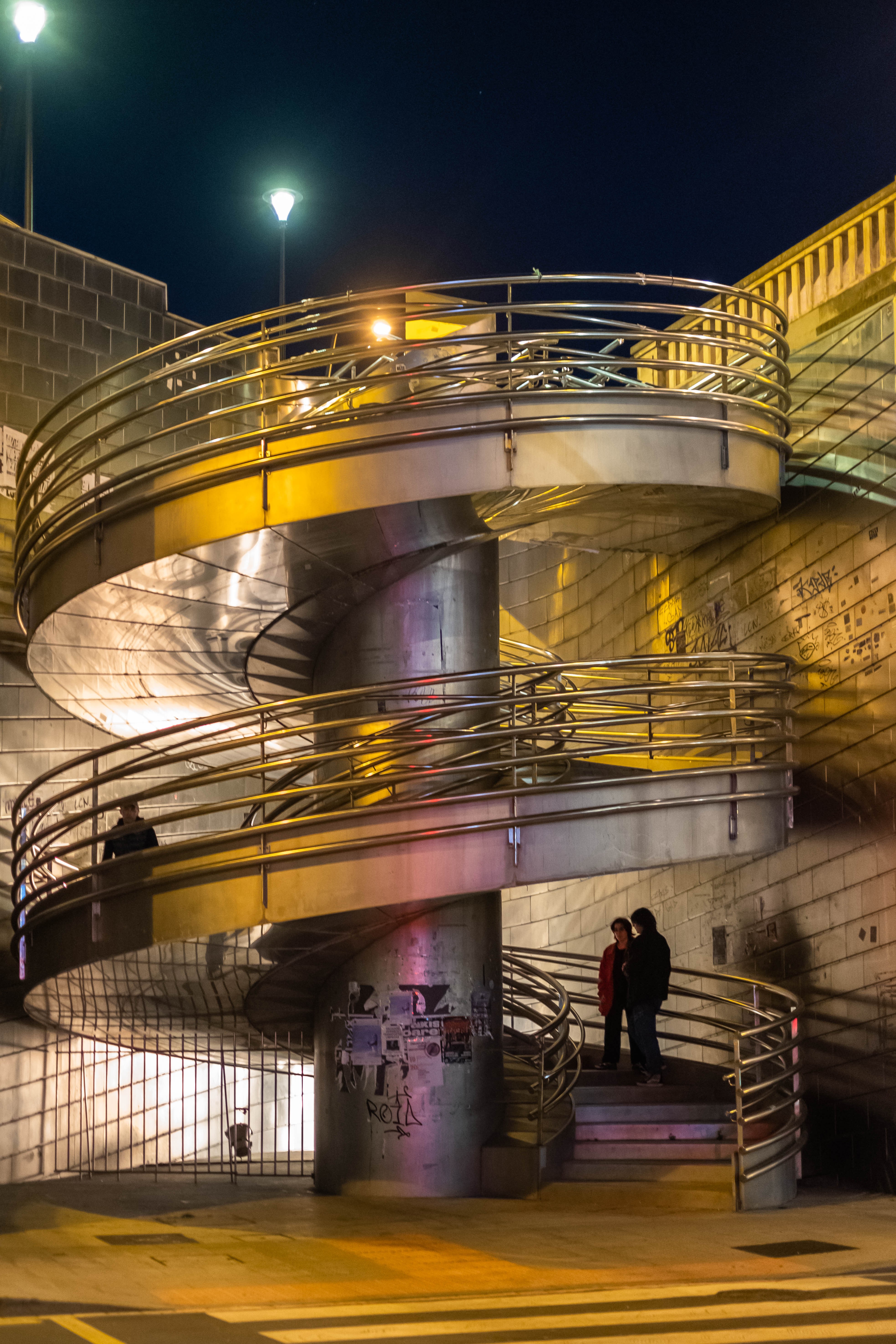 Varias personas acceden por una escalera de caracol al Puente de Deusto. Bilbao, Bizkaia.